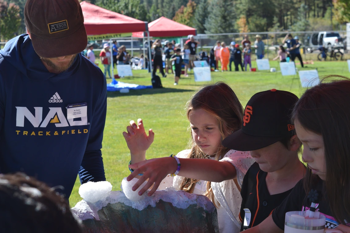Volunteer and students playing with snow on a watershed model